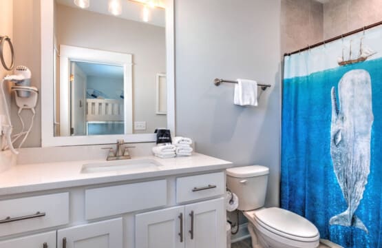 This bathroom's got all the essentials down—a huge vanity, a killer walk-in shower, and that fun whale shower curtain that gives major coastal vibes without taking itself too seriously.