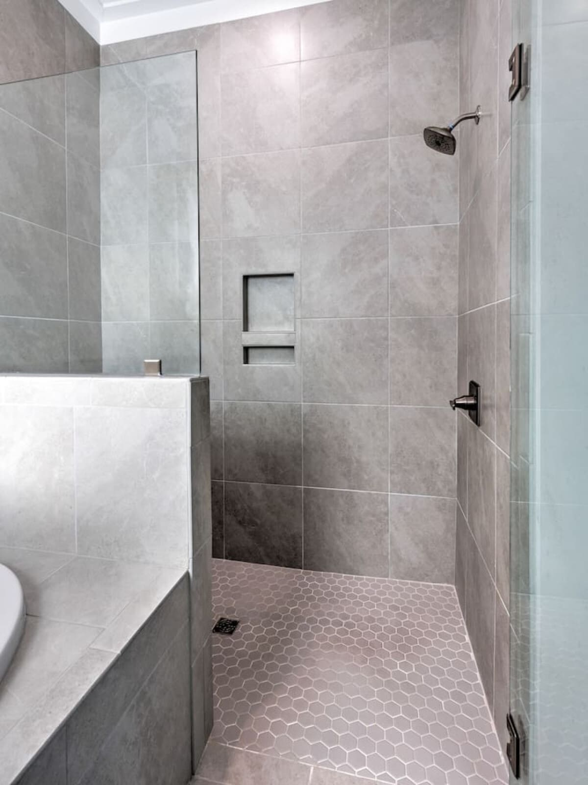 This sleek walk-in shower setup with those built-in niches and hexagon tile floor is basically everything you need to feel put-together during your stay.