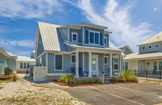 This modern beach house with its charming blue-and-white color scheme, spacious covered porch, and that fresh coastal aesthetic is basically the definition of a relaxing getaway—especially with those cozy rockers calling your name.