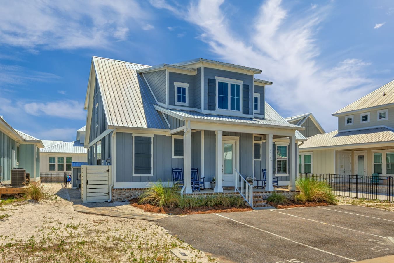 This modern beach house with its charming blue-and-white color scheme, spacious covered porch, and that fresh coastal aesthetic is basically the definition of a relaxing getaway—especially with those cozy rockers calling your name.