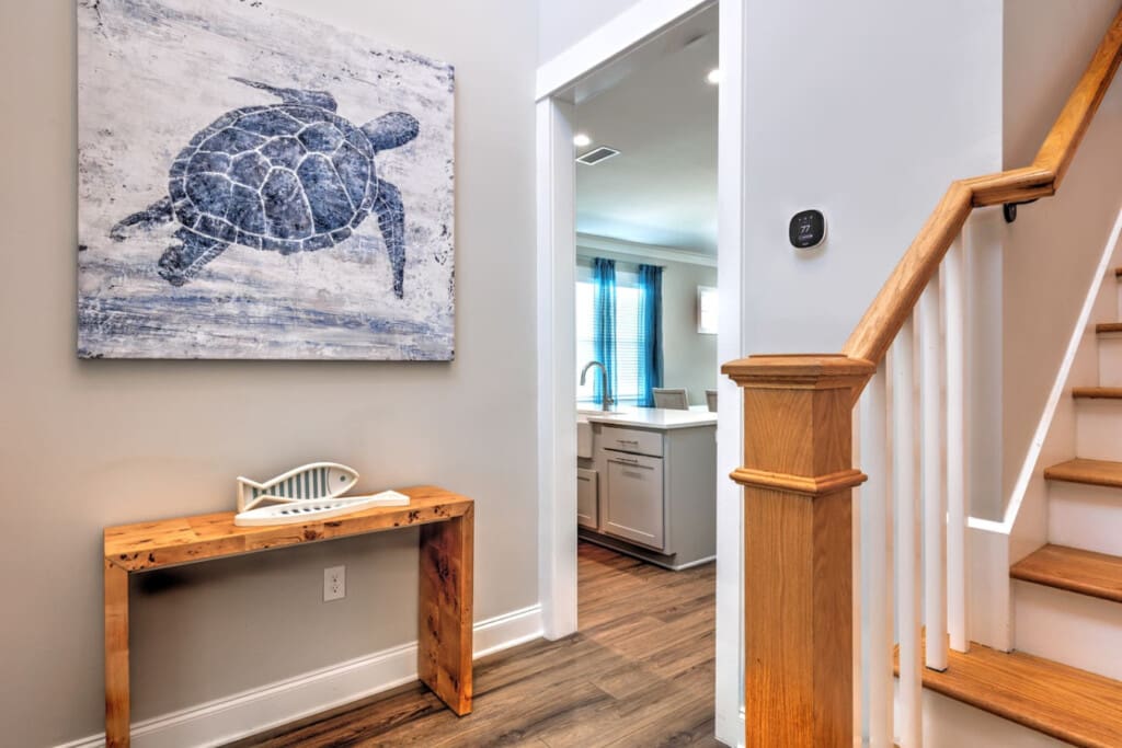 This entryway totally sets the tone for the whole place with that beautiful sea turtle artwork, warm wood details, and clean coastal vibes that immediately make you feel like you're somewhere special.