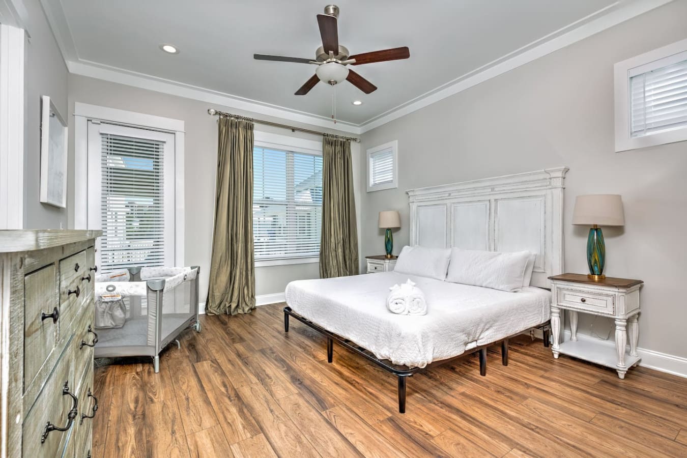 This spacious master bedroom with its crisp white bedding, natural light flooding in from those huge windows, and that serene coastal aesthetic is basically everything you need to actually feel relaxed during your stay.