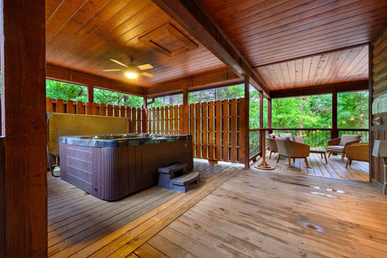 So you've got a hot tub on one end of this massive covered deck and a whole seating area on the other—basically everything you need to never leave the porch.