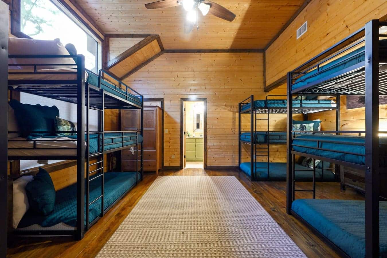 This bunk room's got enough beds spread out that everyone gets their own spot without feeling like sardines, plus it's bright enough that you don't feel like you're sleeping in a basement.