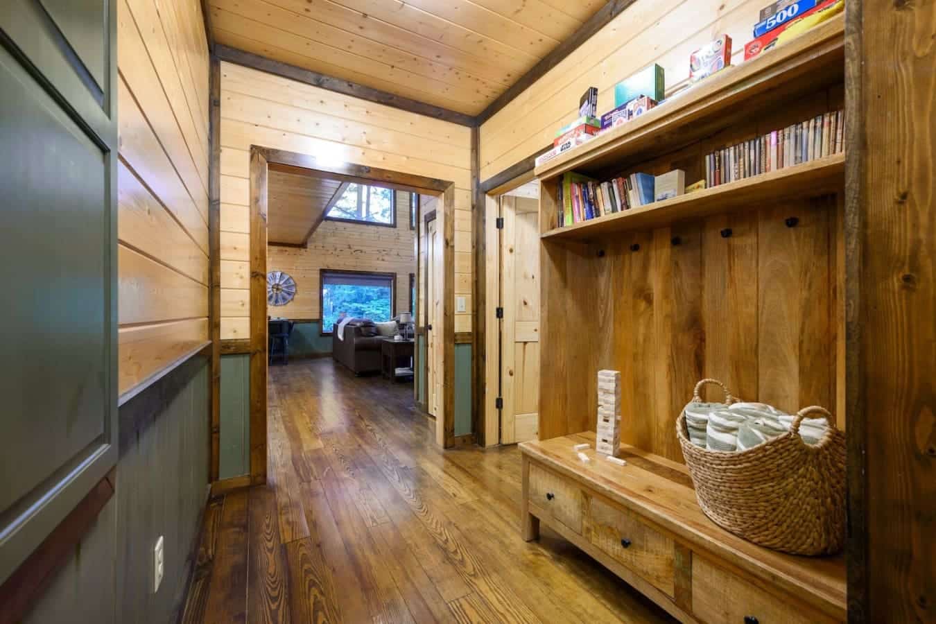 This hallway's basically the heart of the cabin—tons of natural wood, shelves packed with books and games, and those built-in closets mean everyone actually has a place to stash their stuff instead of living out of suitcases.