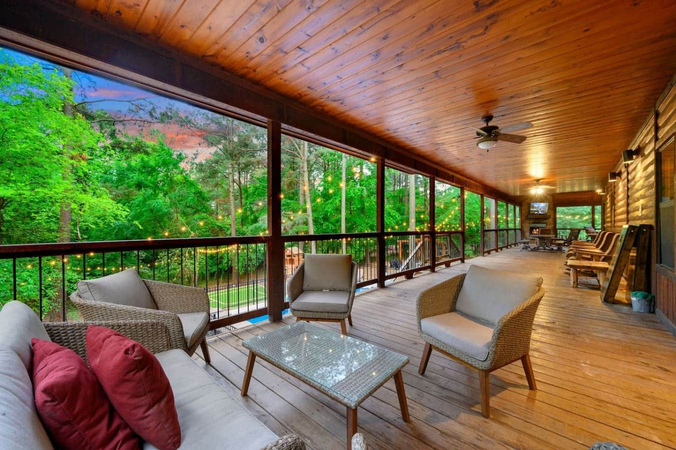 This covered porch is basically where you'll end up spending half your trip—long, open, packed with comfortable seating, and surrounded by so many trees that you'll forget the outside world even exists.