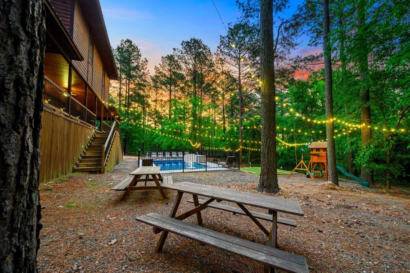 Strung lights twinkle through the trees while you hang out by the pool with picnic tables and a treehouse playground keeping everyone entertained without leaving the backyard.