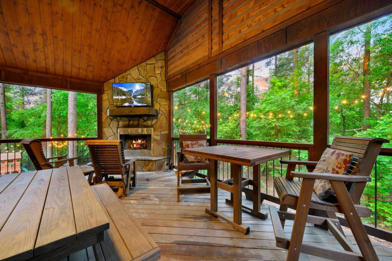 This screened porch is basically your own little treehouse lounge—fireplace going, table ready for whatever, and windows on every side so you're never not looking at trees.
