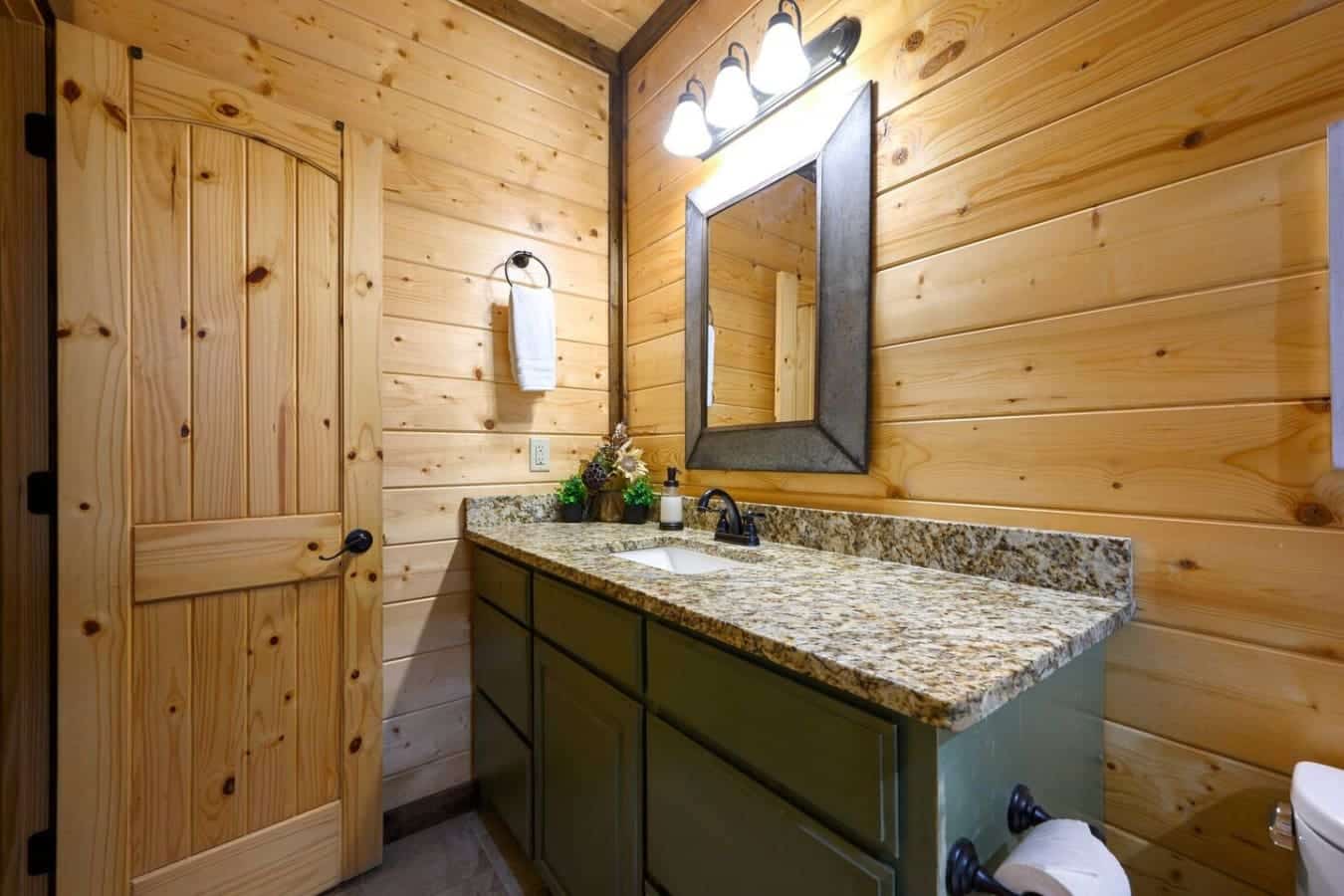 This bathroom's got solid wood walls, a long granite counter with room to breathe, and that rustic mirror situation that actually looks good without trying too hard.