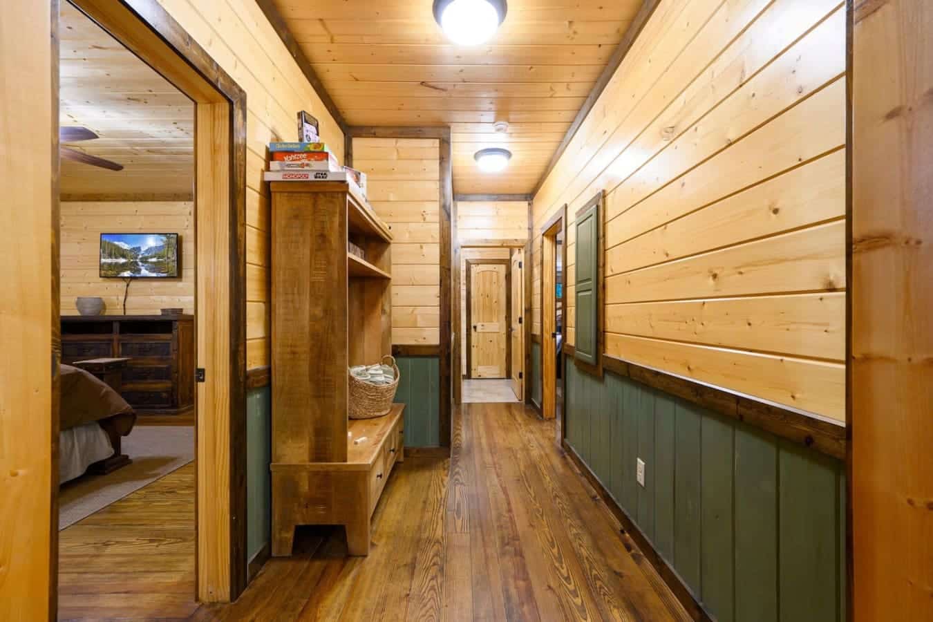 This hallway's basically the spine of the whole place—wood everywhere, multiple doors leading to different rooms, and enough space that you're not constantly bumping into people trying to get somewhere.