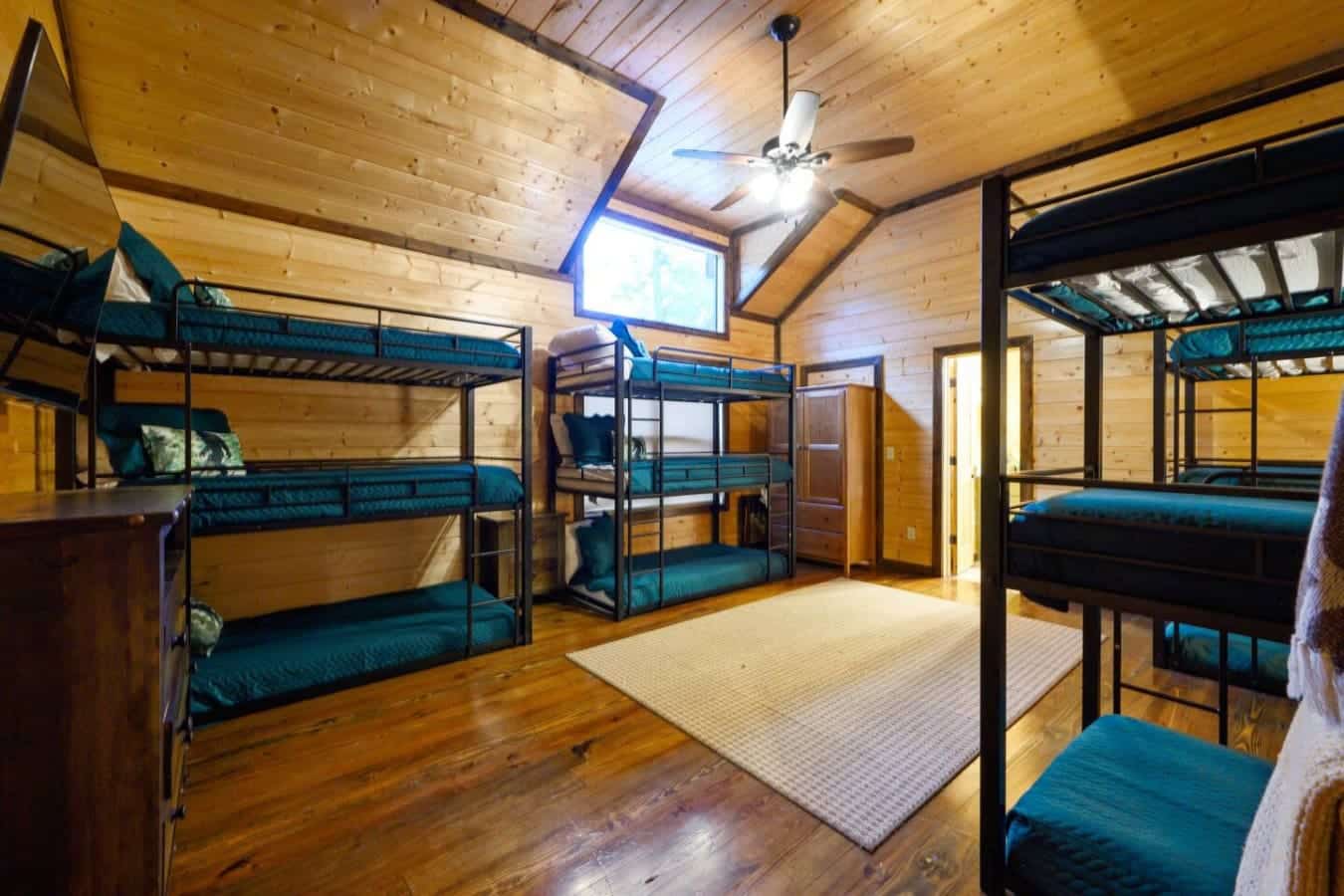 This bunk room is basically set up so a whole crew can crash without anyone getting stuck with the sketchy bed—multiple bunks spread out, plenty of floor space to move around, and enough natural light coming in that it doesn't feel like you're sleeping in