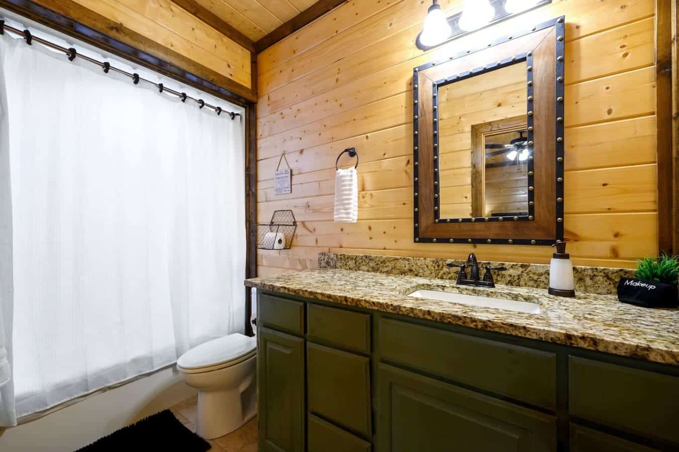 This bathroom's got the whole setup working for you—granite countertops that actually hold up, a big mirror framed out in rustic style, and enough counter space that everyone's toiletries aren't fighting for real estate.