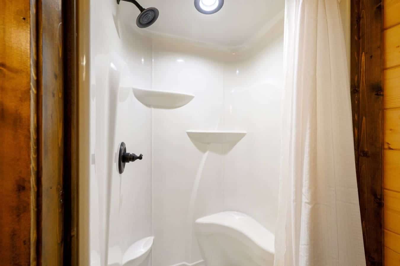 The shower setup here is basically no-frills and gets the job done—rain showerhead up top, a couple of built-in shelves so your stuff isn't scattered everywhere, and way more elbow room than you'd expect.