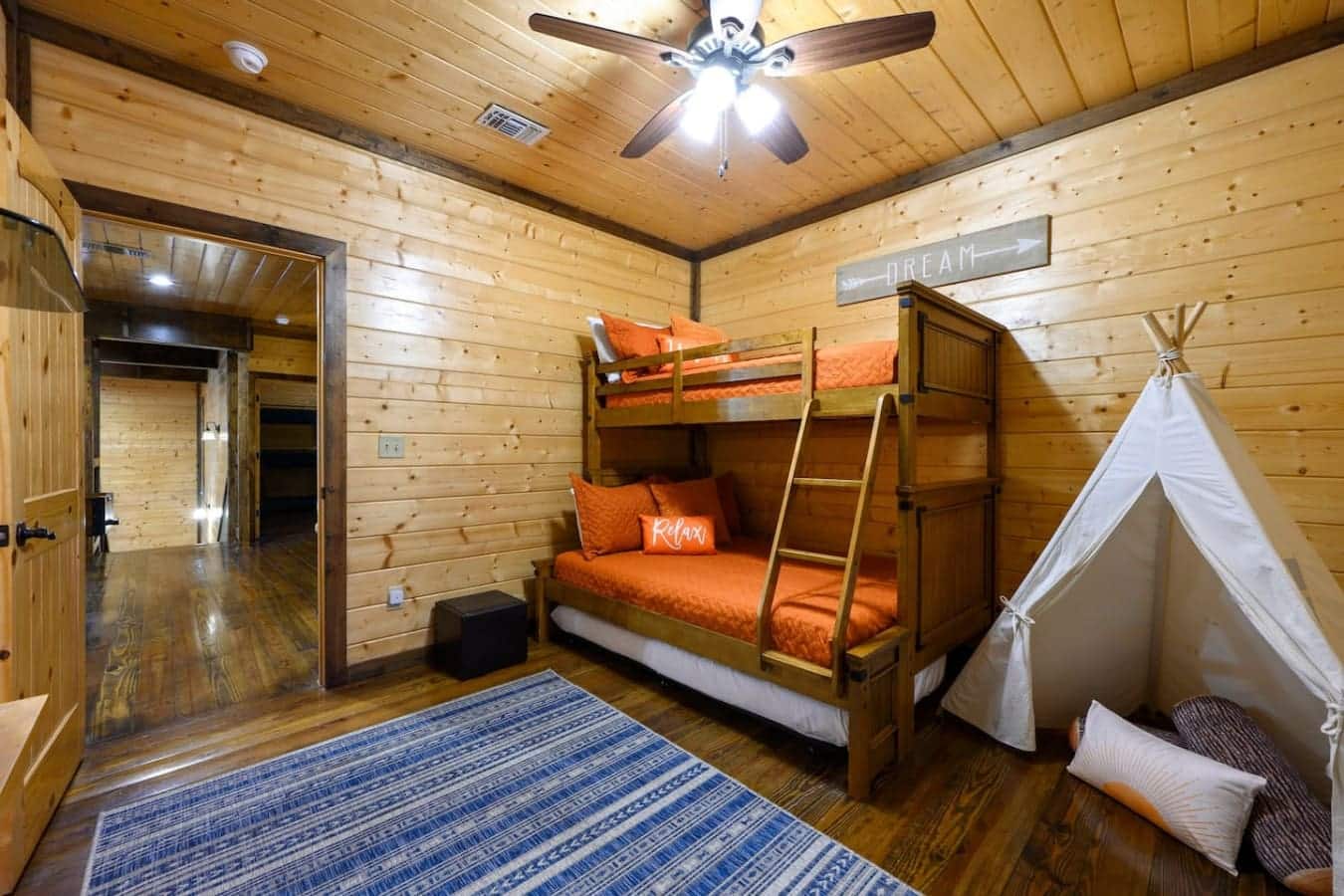 This kids' bedroom's basically got everything dialed in—bunk beds that actually fit real people, a teepee in the corner for when someone needs to escape, and that pops-of-orange color scheme so everyone knows exactly which sleeping spot is theirs.