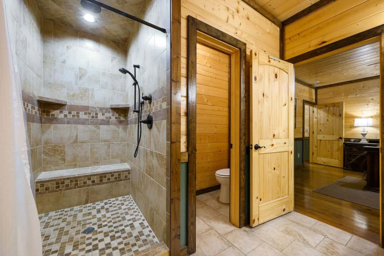 This bathroom setup basically covers all your bases—you've got the rustic wood cabin feel, a nice walk-in shower with good pressure, and a separate toilet room so everyone's not bumping into each other in the mornings.