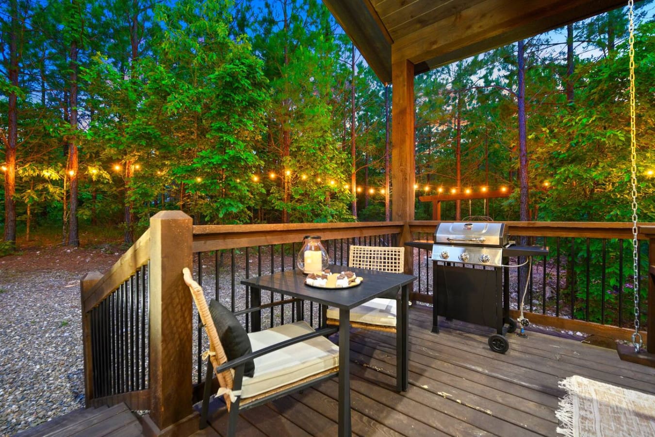 There's something about settling onto this deck at dusk with the forest wrapped around you, string lights glowing through the trees, and your own grill waiting—it's basically the whole "unplugging and actually enjoying it" vibe in one perfect setup.