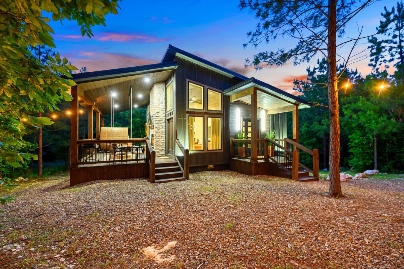 This cozy modern cabin glowing in the forest at dusk is basically screaming "come hide away and actually relax for a few days."