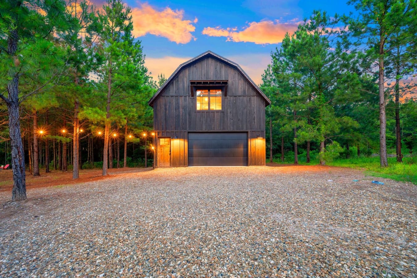 Tucked among the trees, this modern barn-style retreat glows at golden hour.