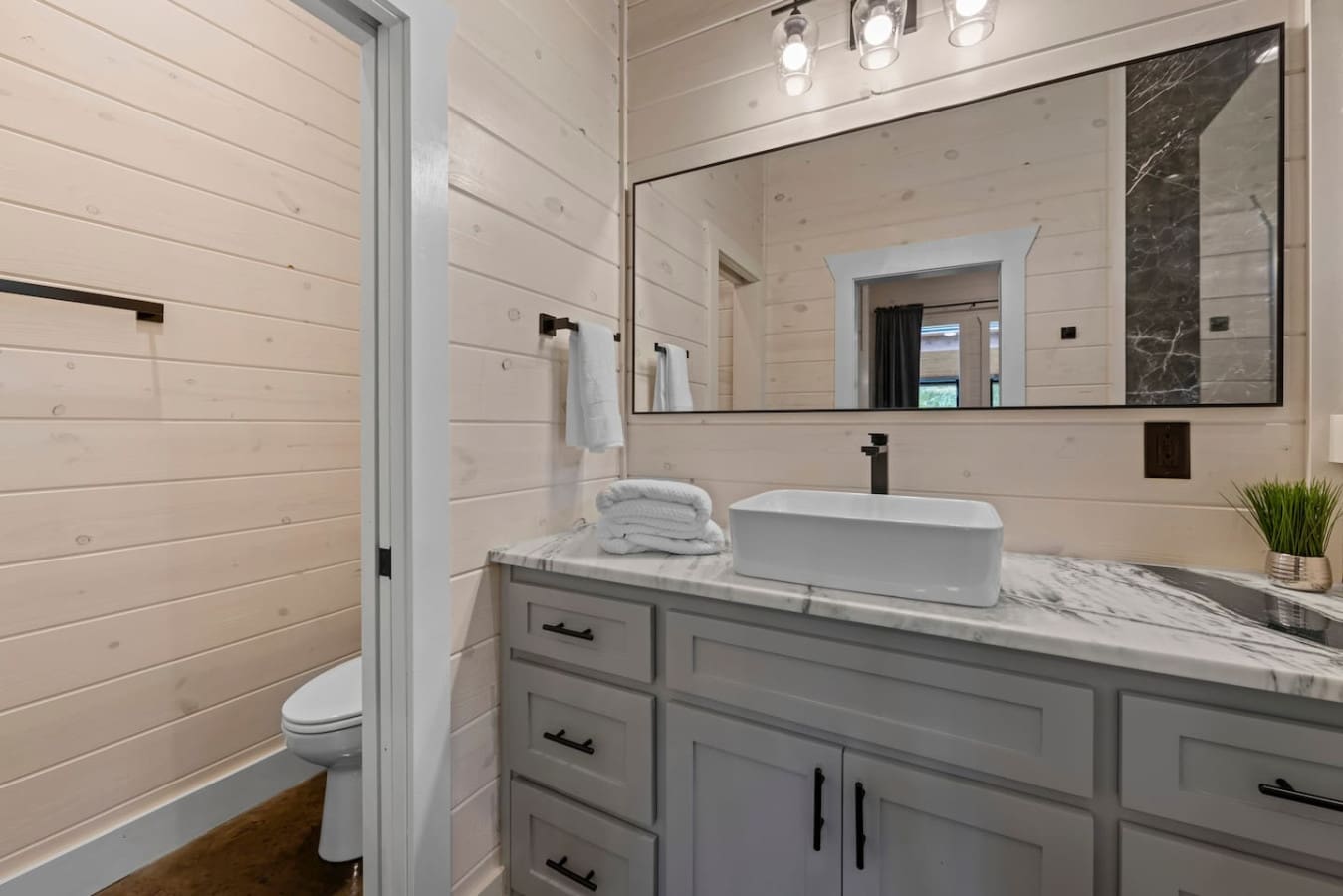Bright and inviting: this bathroom blends soft wood textures, modern black fixtures, and a marble countertop for a clean, sophisticated look.