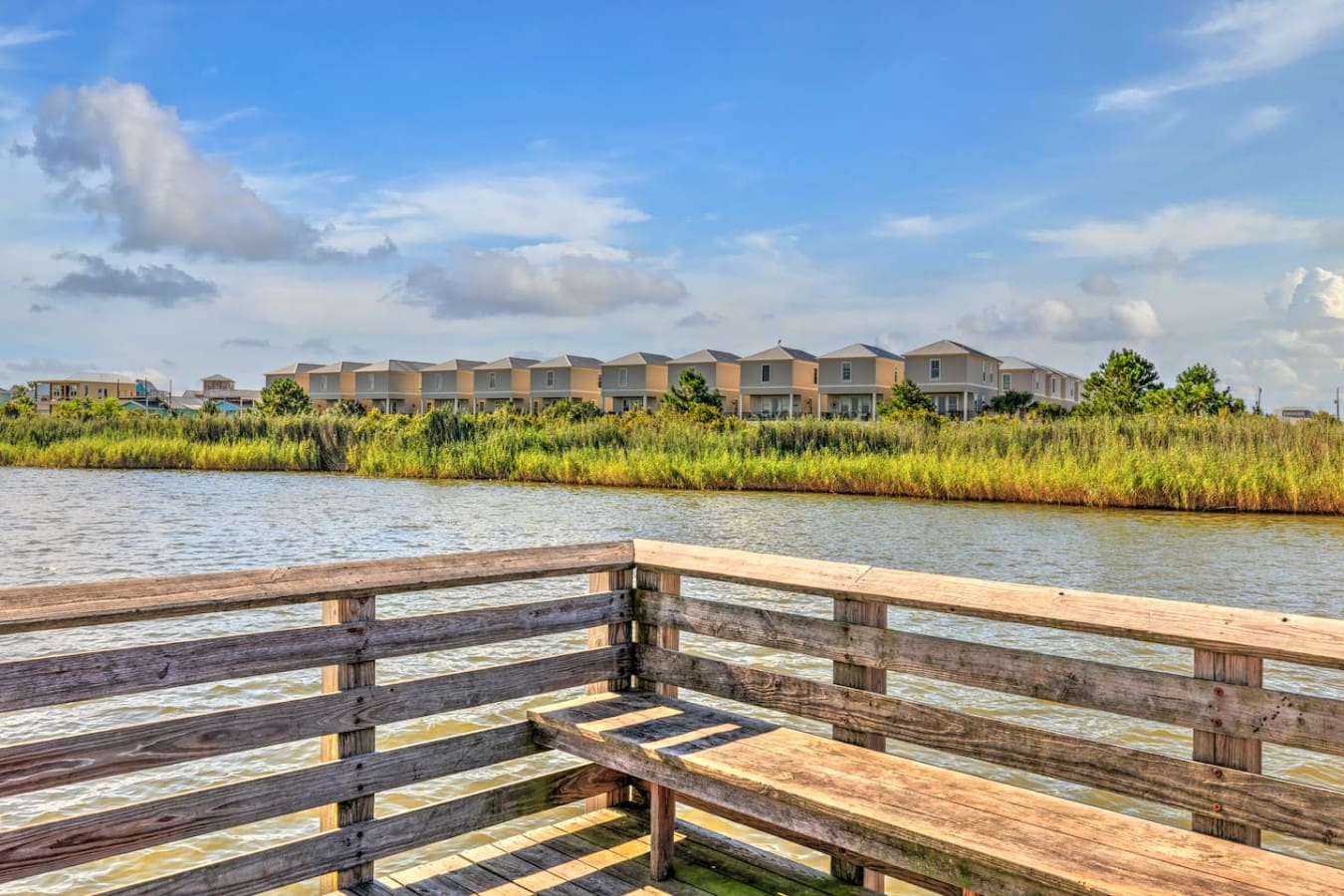 There's something about stepping onto a weathered dock with nothing but marsh grasses, water, and a row of cozy beach houses stretching out in front of you that just hits different.