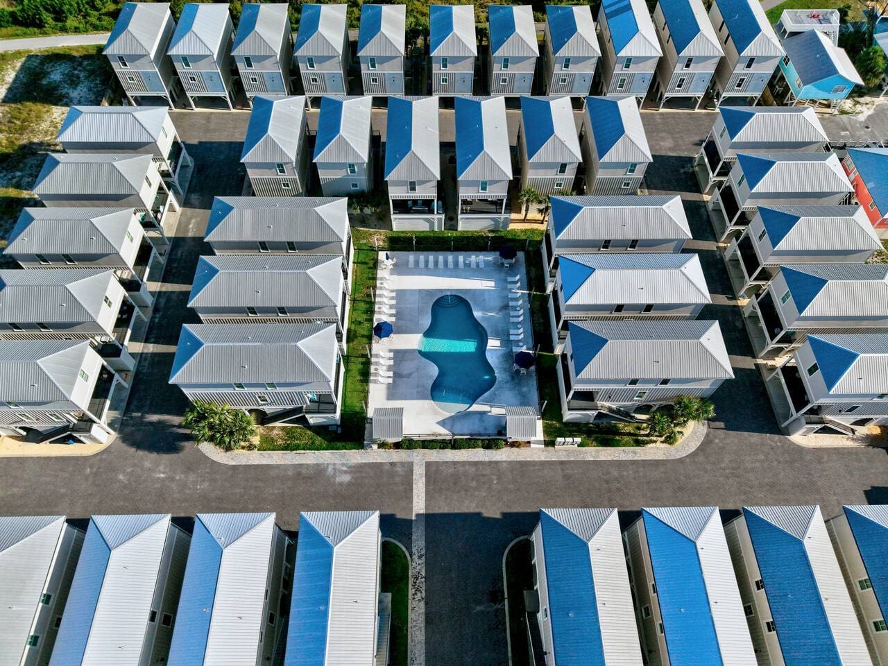 This little community has the ultimate setup—your own modern beach house, a shared pool right in the center, and all those perfectly aligned roofs creating this weirdly satisfying grid of coastal calm.