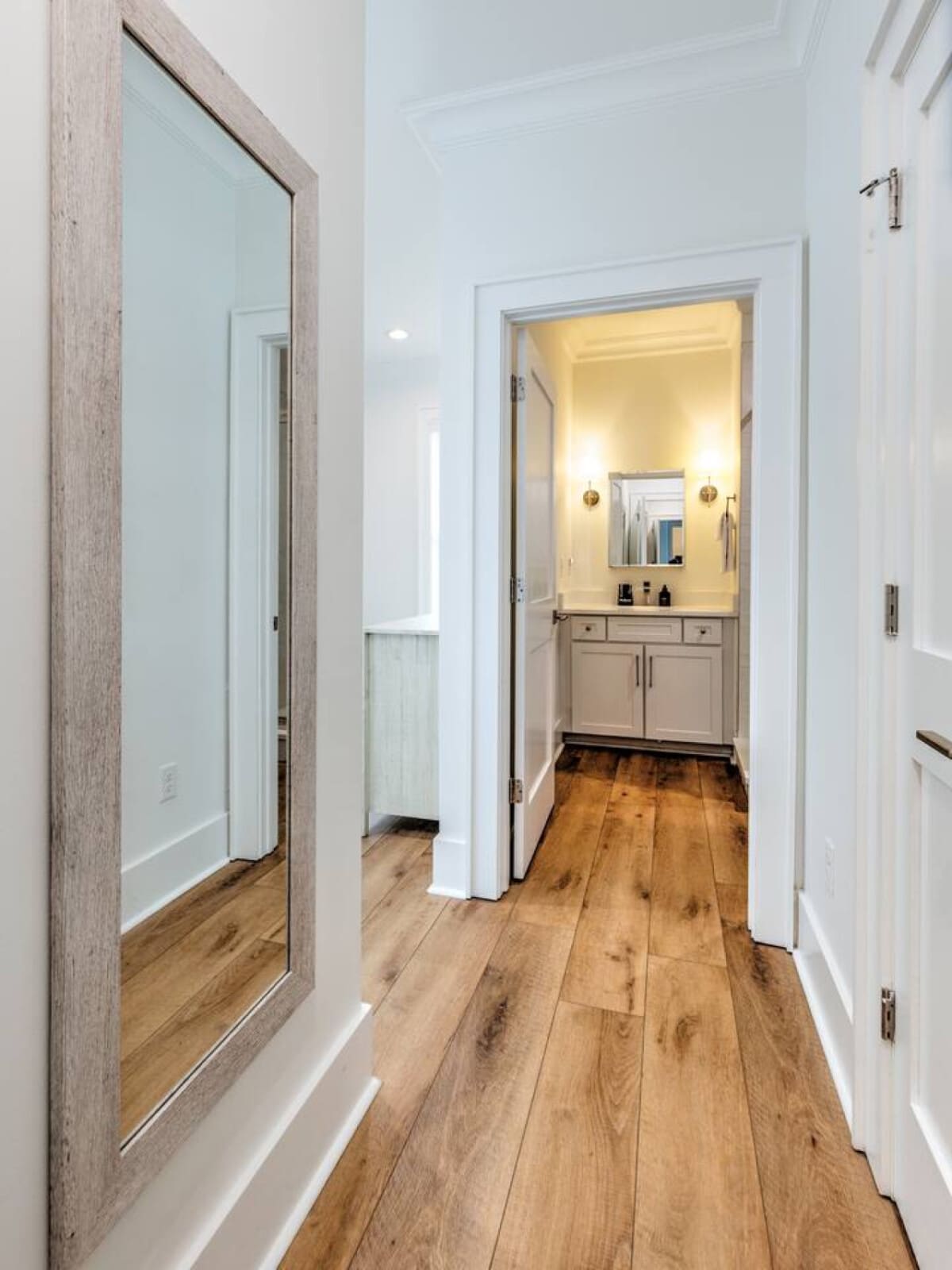 This hallway is basically a master class in making a tight space feel open and airy, with that gorgeous wood flooring stretching all the way back to a spa-like bathroom that's going to make your morning routine feel way more luxurious than it has any righ
