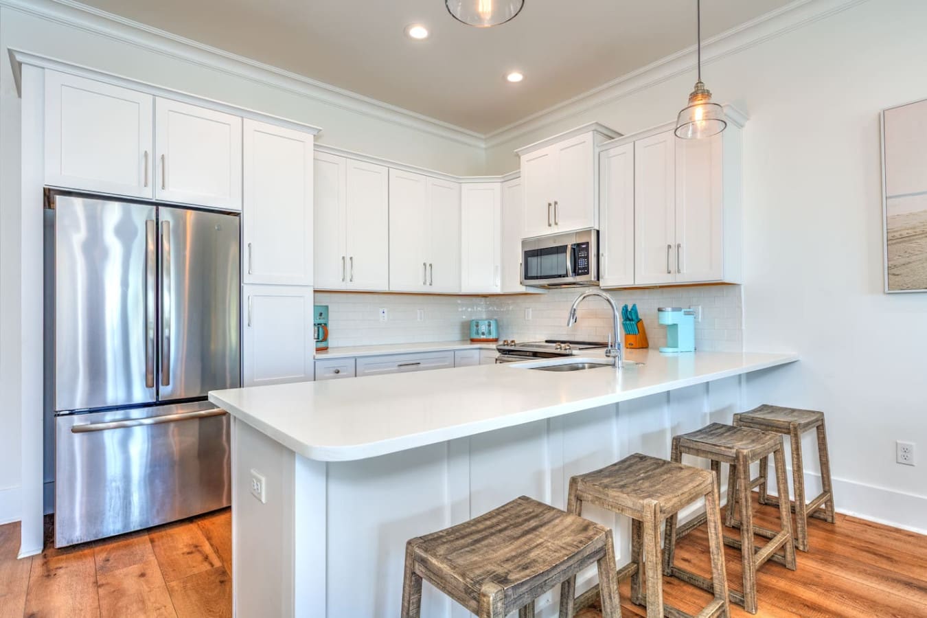 This spotless white kitchen has everything you need to actually cook real meals during your trip, plus those wooden bar stools and island setup make it the kind of space where everyone naturally gathers.