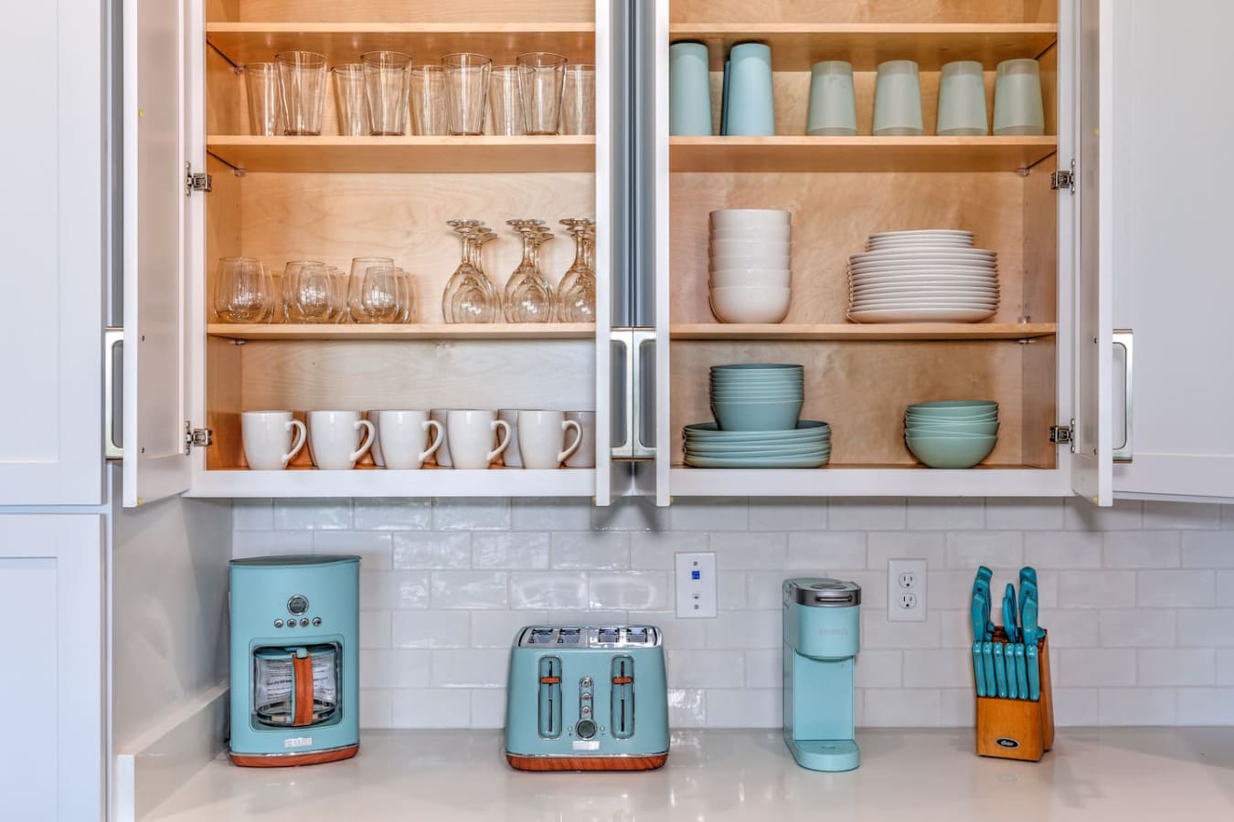 This kitchen is basically a color-coordinated dream with those matching turquoise appliances and organized open shelving that somehow makes you actually want to keep things neat.