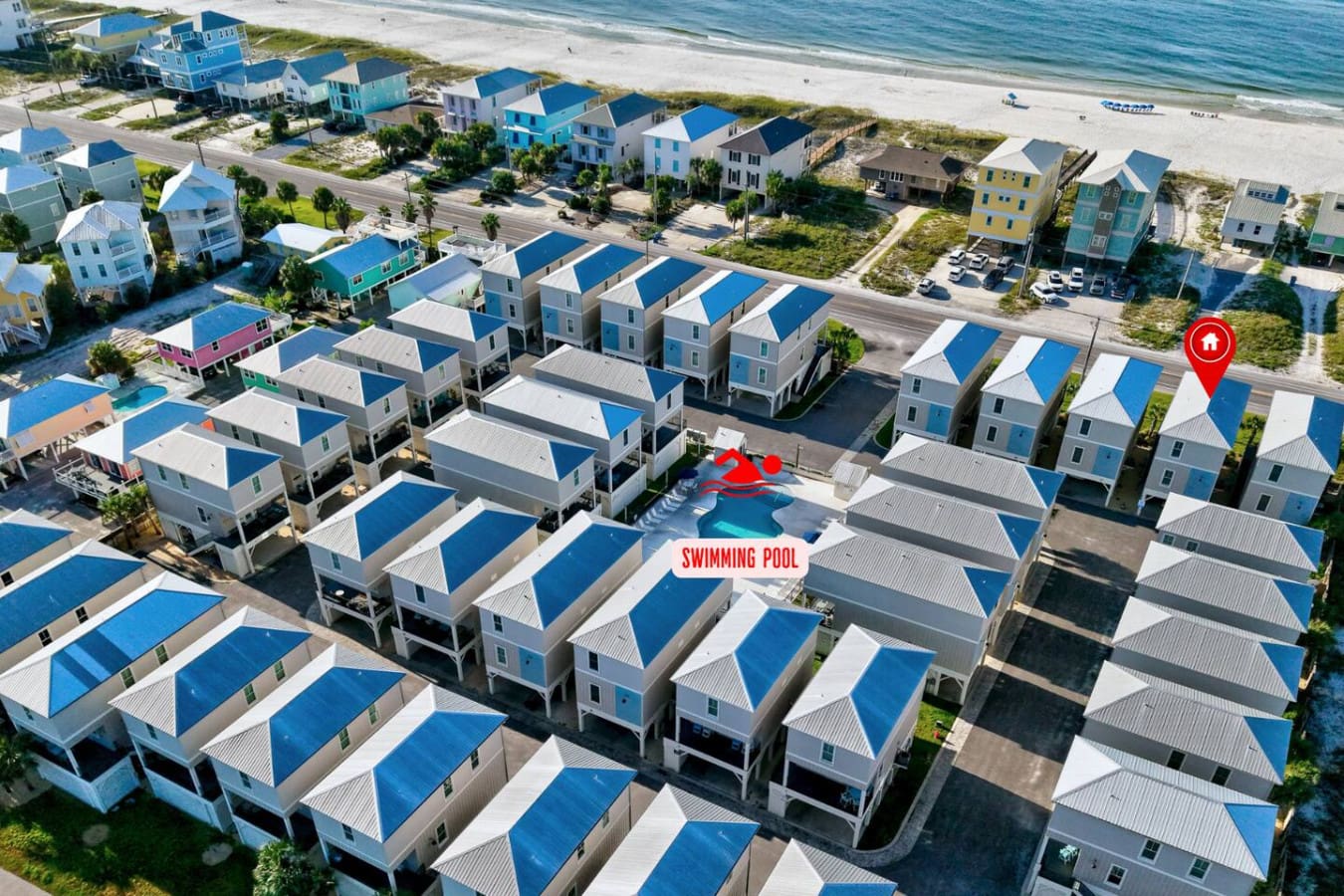Looks like someone found the ultimate beach vacation spot with a community pool, dozens of cute blue-roofed houses, and the ocean literally right there waiting.