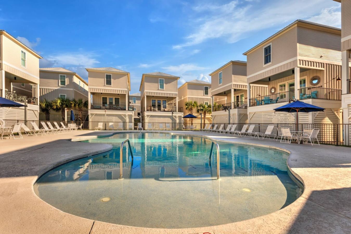 This is giving major "beach town vibes without the crazy crowds" energy—quiet pool, stacked lounge chairs, and adorable elevated homes as far as you can see.