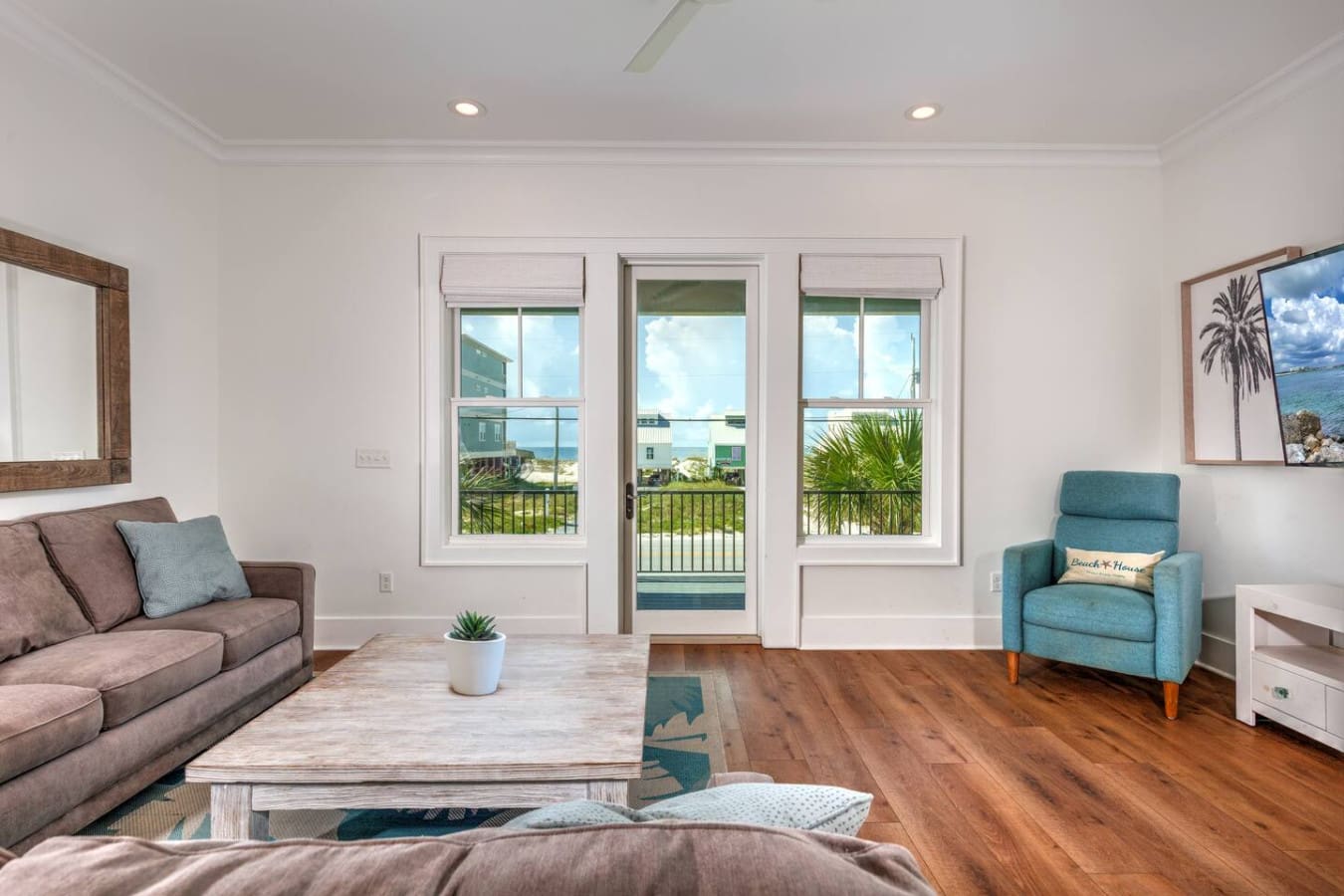 This oceanfront living room is basically the dream setup—just you, your crew, and those massive windows with the beach and sky taking up all the real estate you need to stare at.
