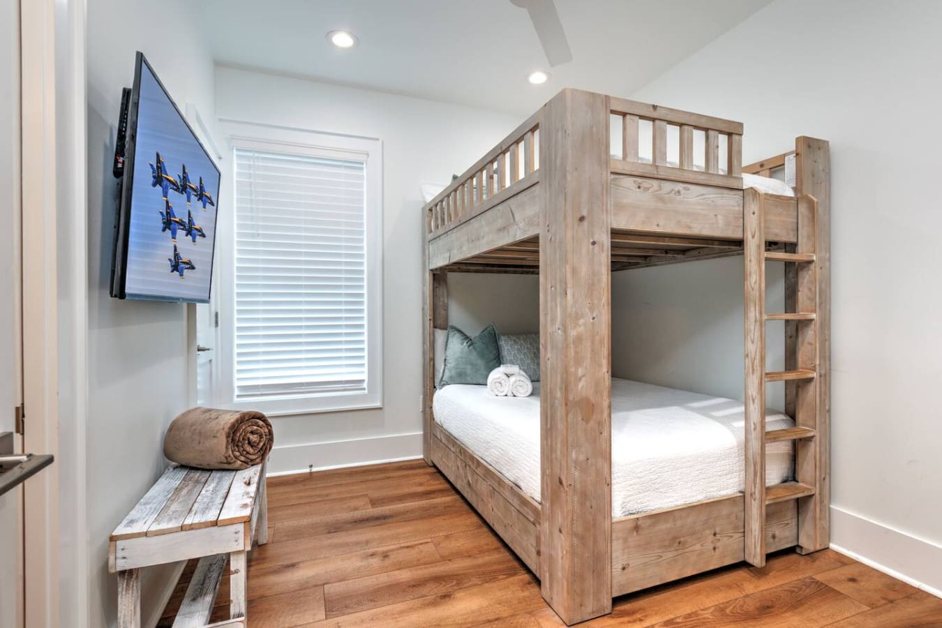 This bunk room is basically a kid's dream setup with that awesome wooden loft bed, built-in shelving for all their stuff, and a TV to keep them entertained during downtime.