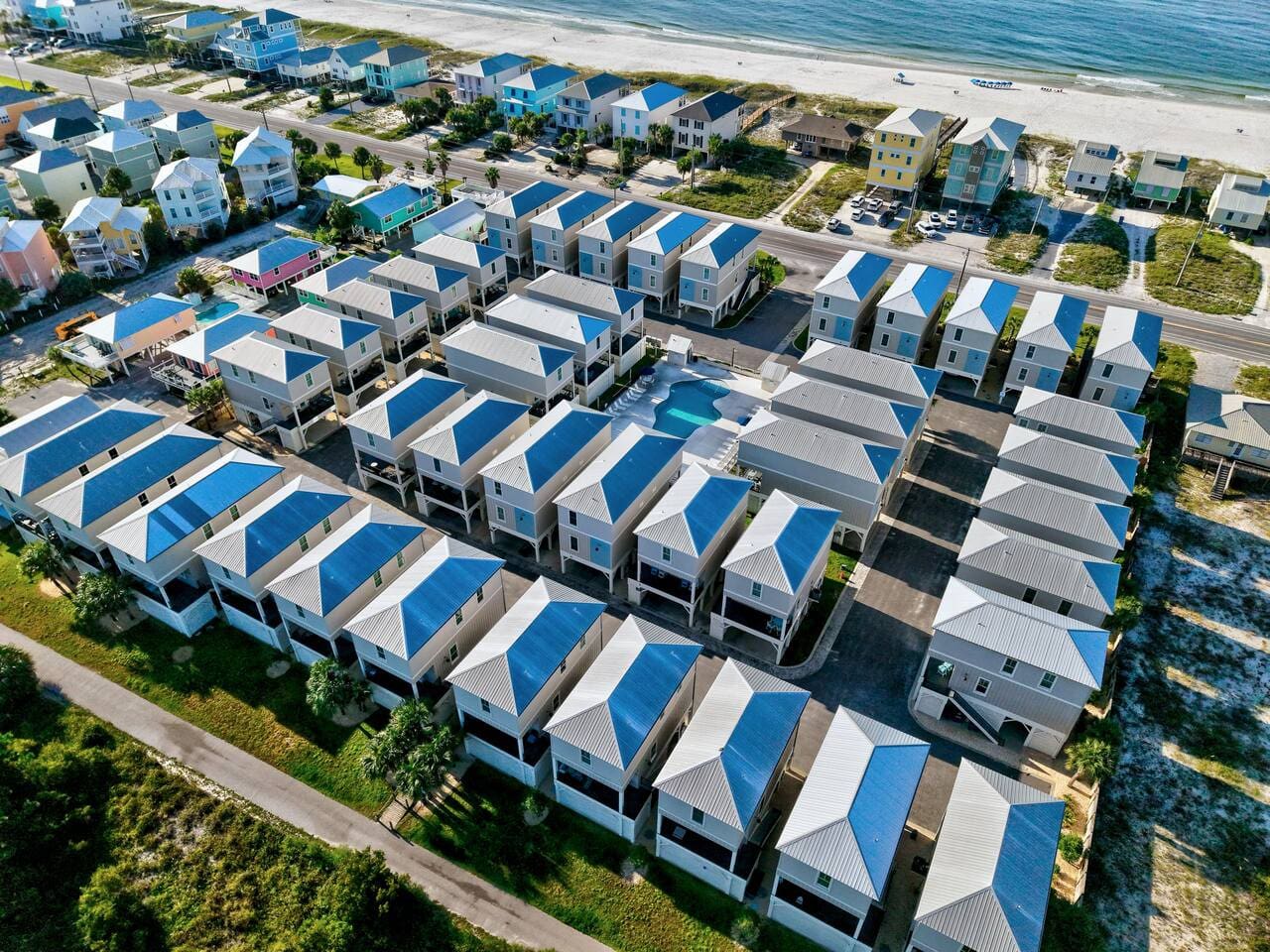 These rows of blue-roofed beach houses look like someone took the quintessential Outer Banks vibe and made it actually affordable, all clustered together with the ocean basically calling your name in the background.