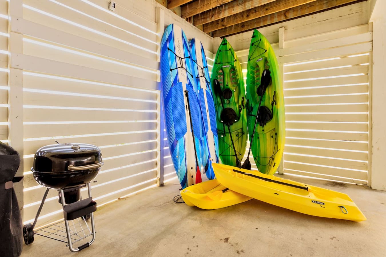 If you're into water sports, this garage setup is basically a dream—kayaks, paddleboards, and a grill all ready to go for your beach getaway.