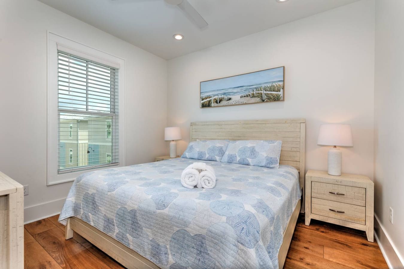 This bedroom is giving beachy, calm vibes with that light wood headboard, soft seafoam bedding, and a window framing the water—basically everything you need to wake up feeling like you're already on vacation.