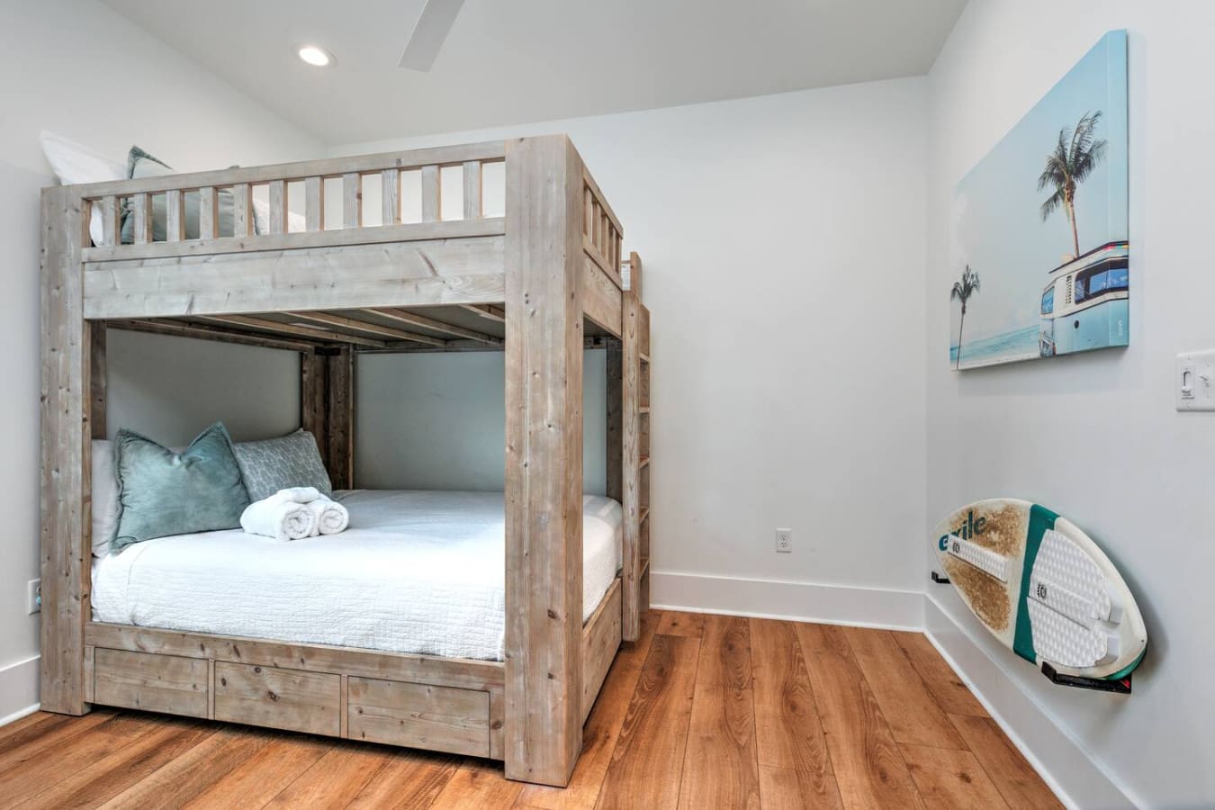 This whitewashed bedroom with the rustic wood canopy bed is basically giving "peaceful beach house escape" without trying too hard, especially with that surfboard leaning against the wall as a reminder of what's waiting for you outside.