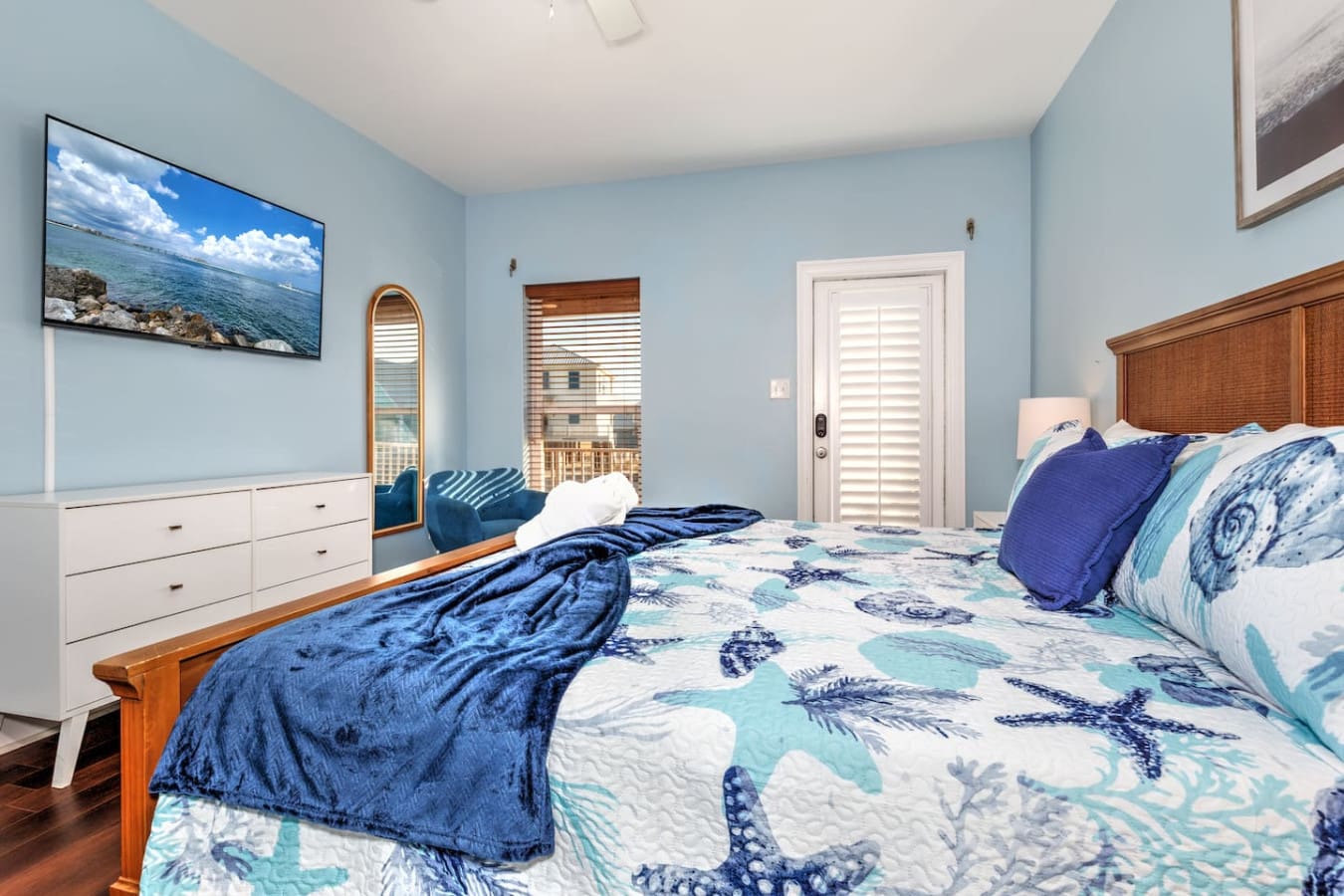 Wake up in this breezy coastal bedroom with its calming blue walls, ocean-inspired bedding, and those plantation shutters framing views that'll make you never want to leave.