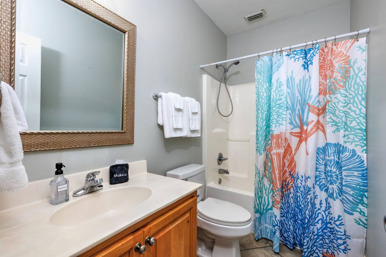 This cheerful bathroom with its coral and teal sea-life shower curtain is basically giving you all the coastal charm you need to start your day feeling like you're still on vacation.