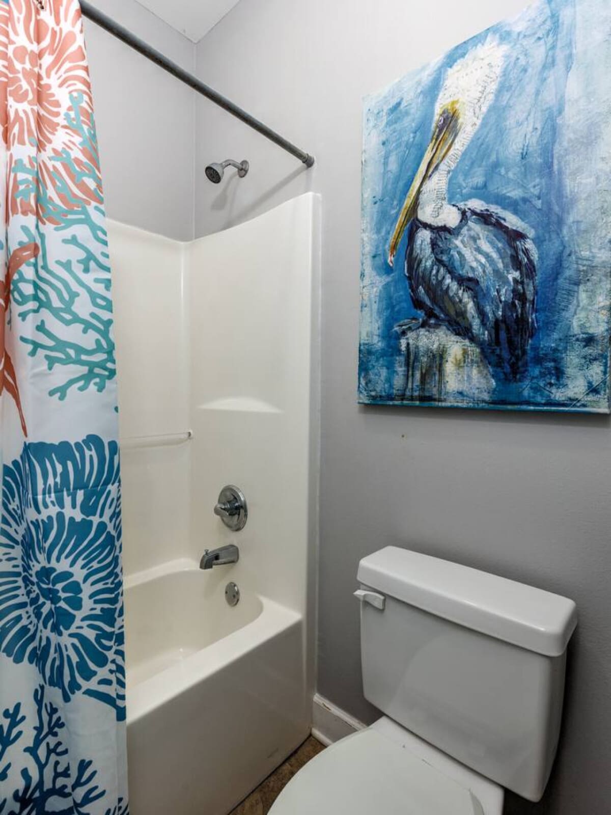 This cute bathroom nails the coastal vibe with that playful coral and teal coral-print shower curtain and a sweet little pelican canvas to remind you where you are.