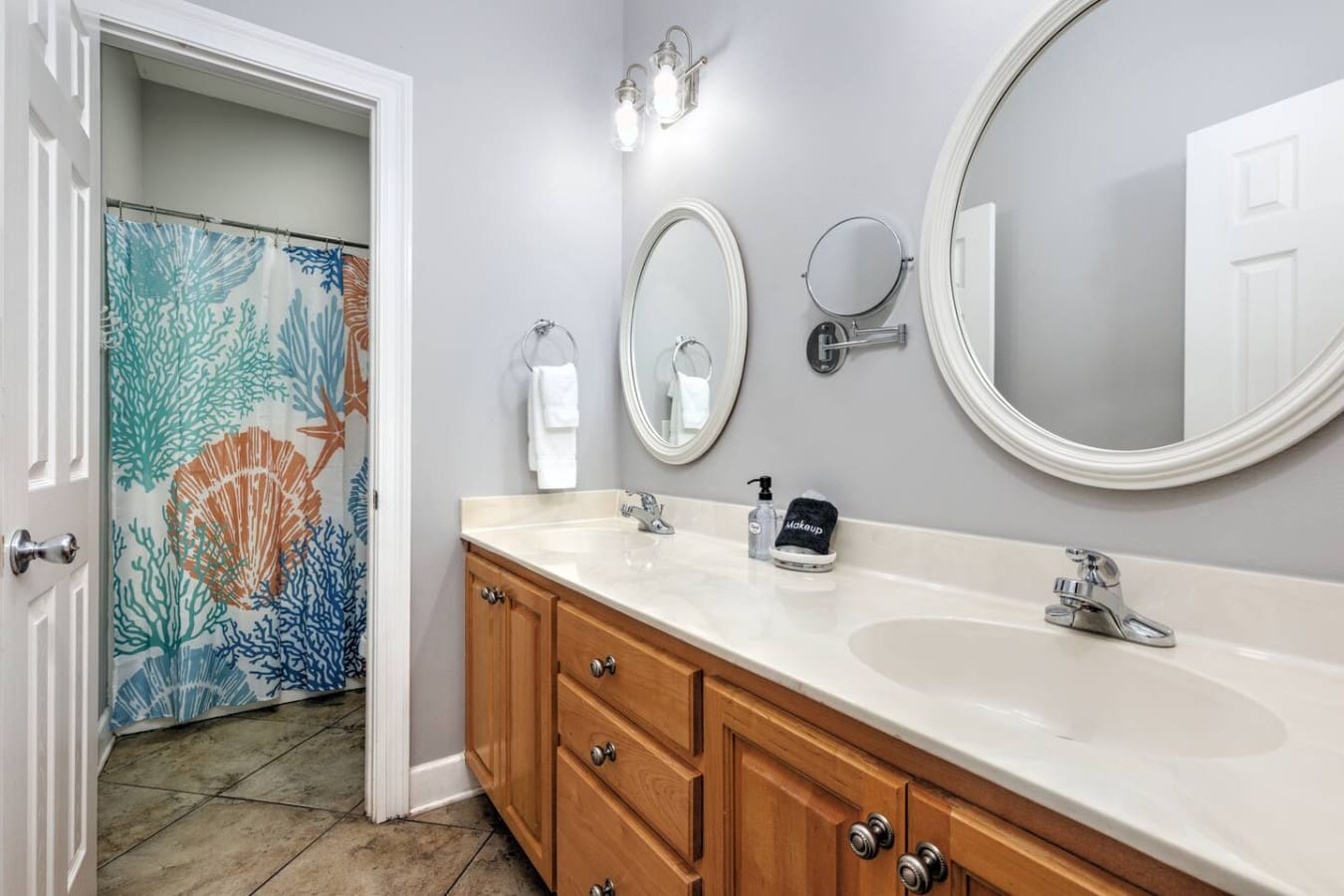 With multiple mirrors, chrome fixtures, and that gorgeous coral-and-teal shower curtain peeking through the doorway, this bathroom has all the coastal charm you need to start your day feeling refreshed.