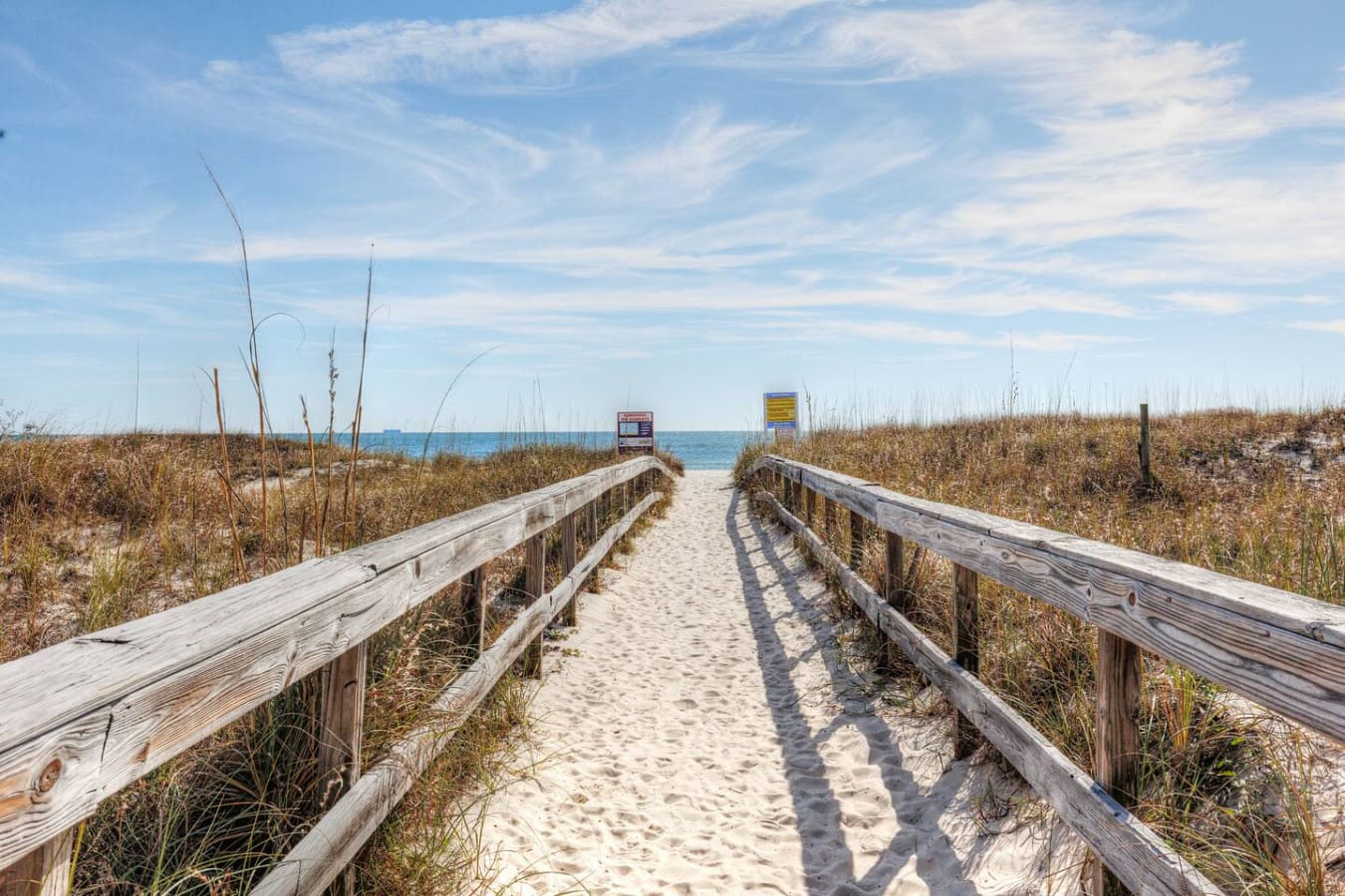 The weathered boardwalk lined with sea oats leads straight to the ocean, making those lazy beach days feel like they're just a quick walk away.