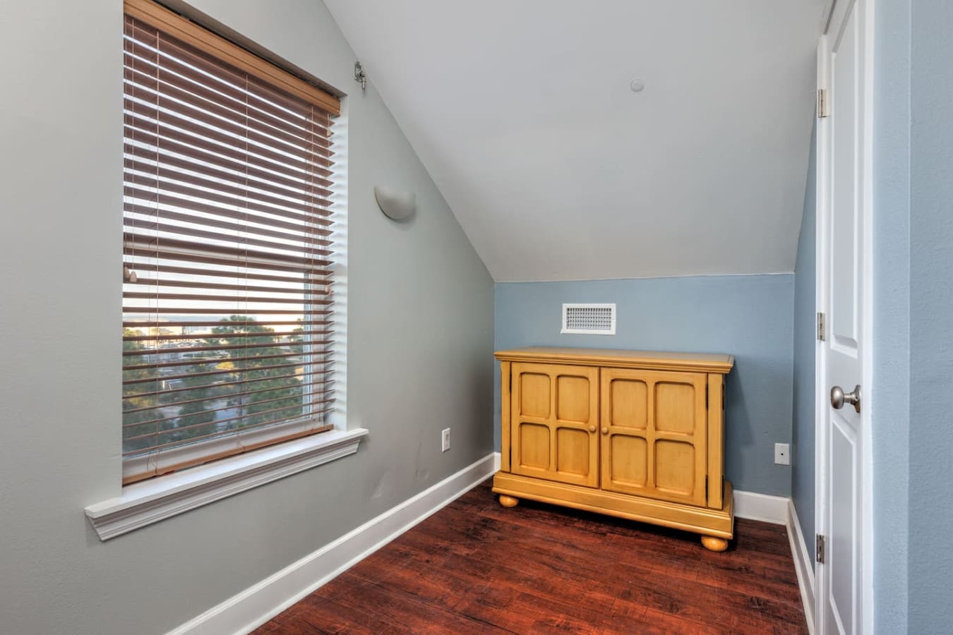 This bright upstairs bedroom with its soft blue accent wall and charming wooden dresser has that perfect blend of coastal calm and cozy comfort that makes you never want to leave.