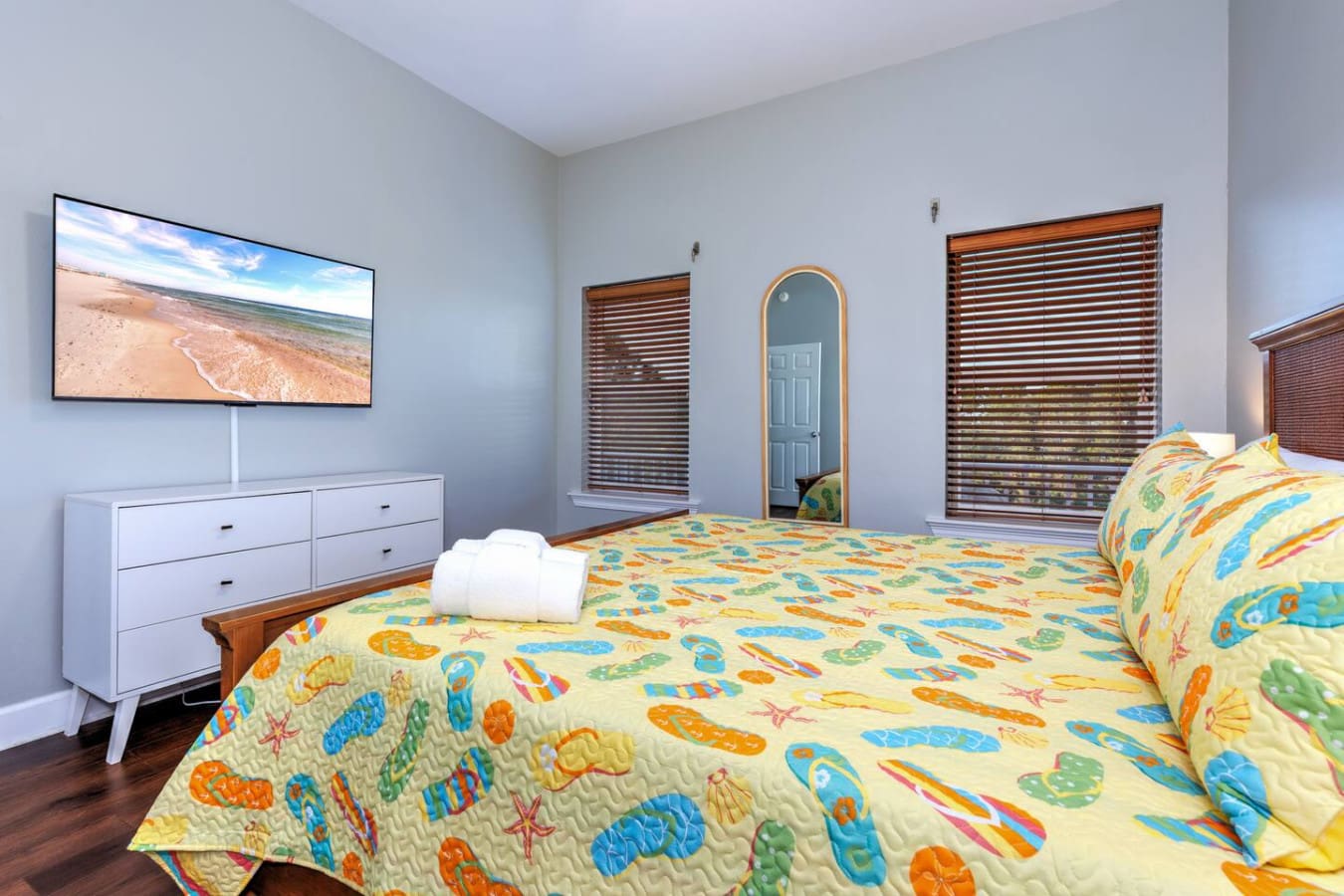 This beachy kids' bedroom with its colorful fish-print bedding and ocean views right on the TV is basically saying "time for an adventure" every morning.