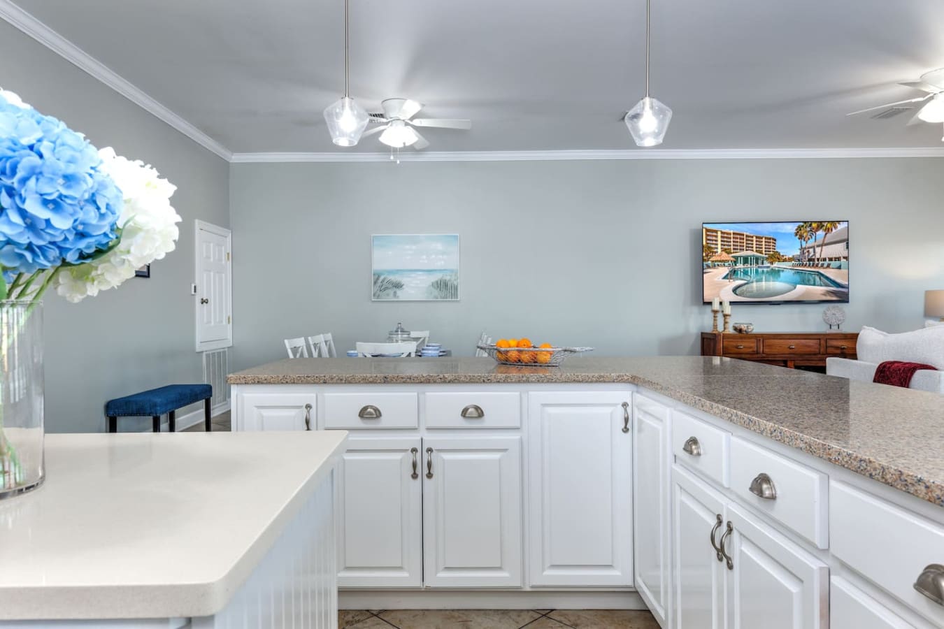 This bright, beachy kitchen with its white cabinetry and granite counters is practically built for gathering the whole family—plus that view of the resort pool on the TV definitely doesn't hurt.