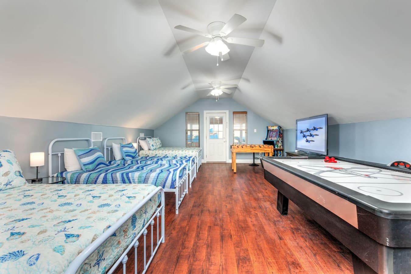 This attic room is basically the ultimate kids' getaway with multiple beds, a full air hockey table, and enough space for the whole crew to spread out and have their own little vacation within the vacation.