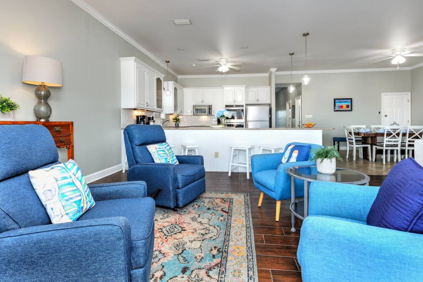 This open-concept living space is basically the ultimate hangout spot where you can kick back in one of those comfy blue chairs, watch the kitchen action happen, and still feel connected to the whole crew.