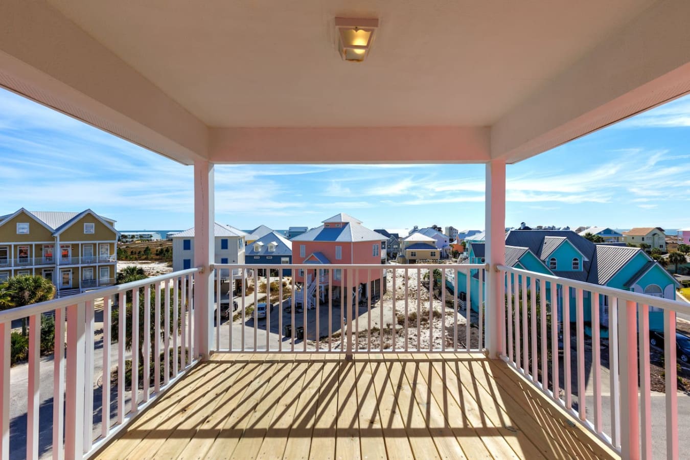 From this pink-railed deck, you've got a front-row seat to this whole charming beach community with its rainbow of colorful houses and that endless blue sky stretching out in every direction.