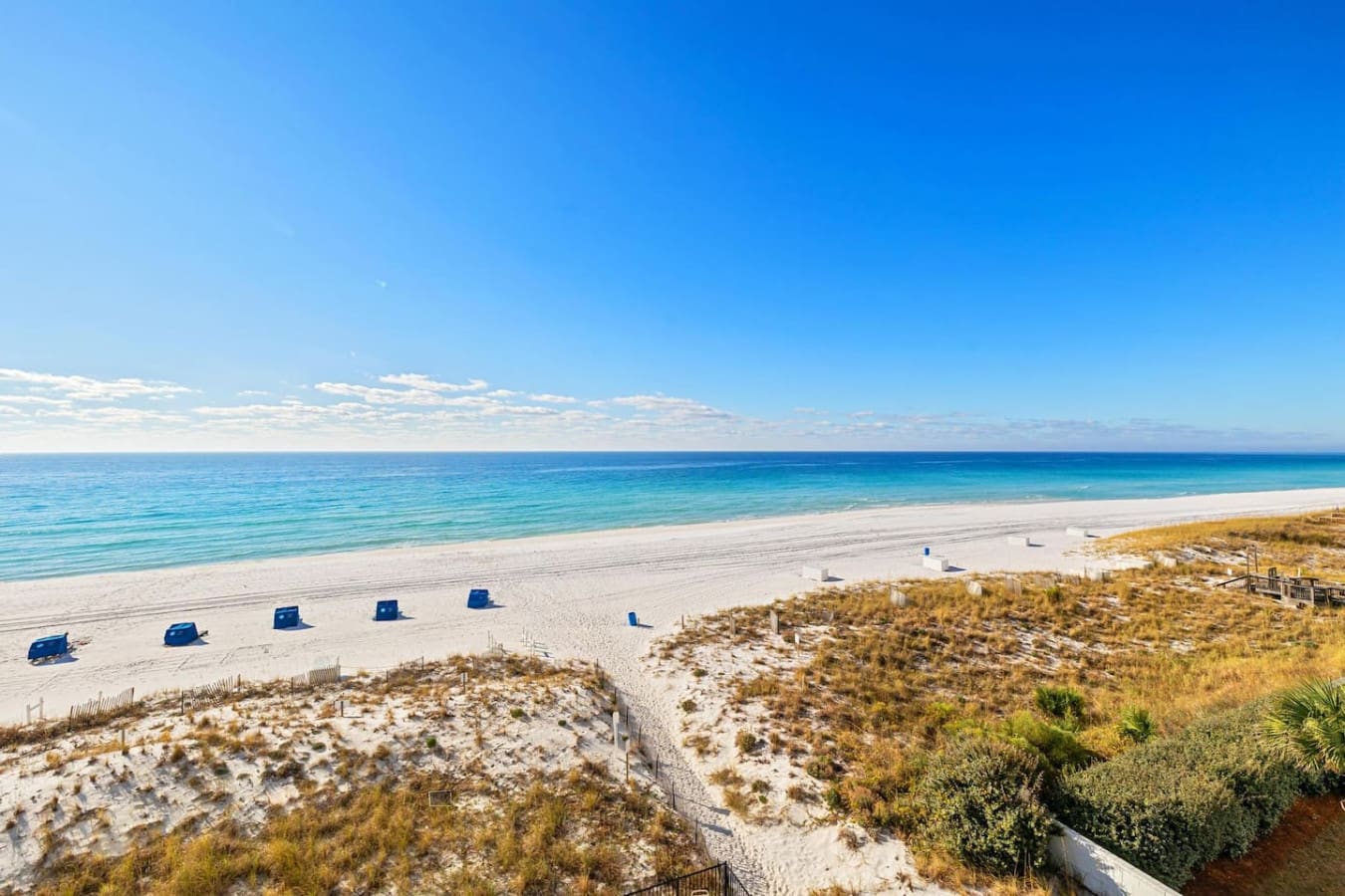 Straight shot from your lounger to the shoreline—this is the kind of beach setup where the ocean feels like it's basically your backyard, complete with those signature blue cabanas keeping the sun at bay while you settle in for the day.