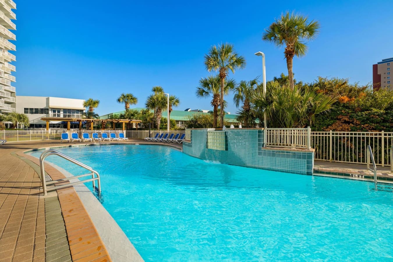 This resort pool setup basically has it all—those perfectly lined loungers, towering palms creating natural shade, and that turquoise water that's literally calling you to dive in and forget what day it is.