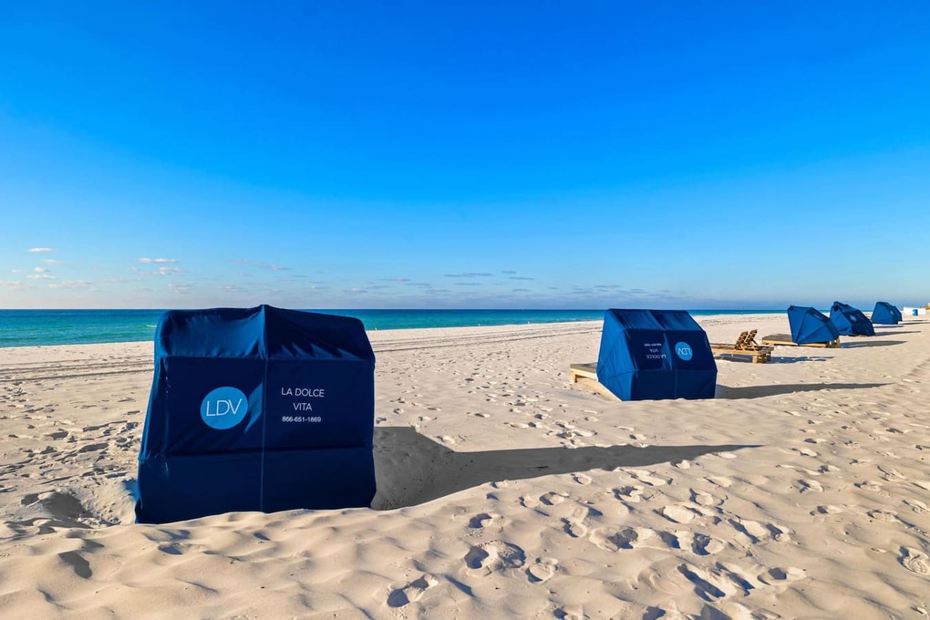 Those iconic blue beach cabanas dotting the sand are the real MVP of a perfect beach day—claim one and you've got your own little shaded sanctuary while the ocean does its thing right in front of you.